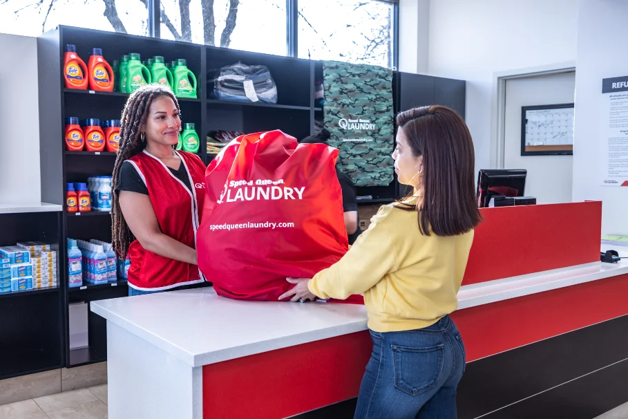 SpeedQueen_Chicago_GrandAve_Nov2021-4248-ok woman in Chicago laundromat receiving bag of laundry